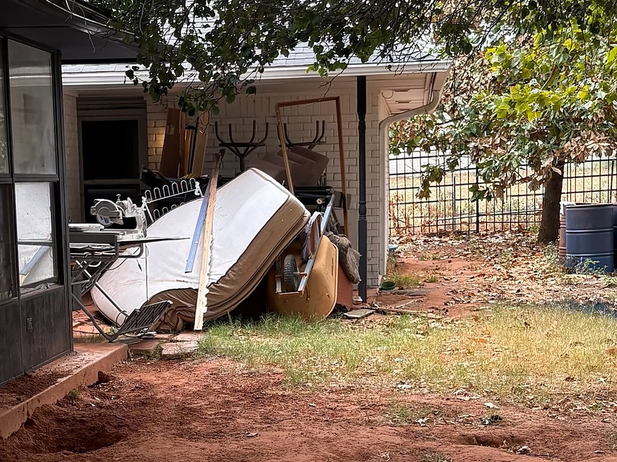 Old mattress and junk on a back patio before removal in Oklahoma City